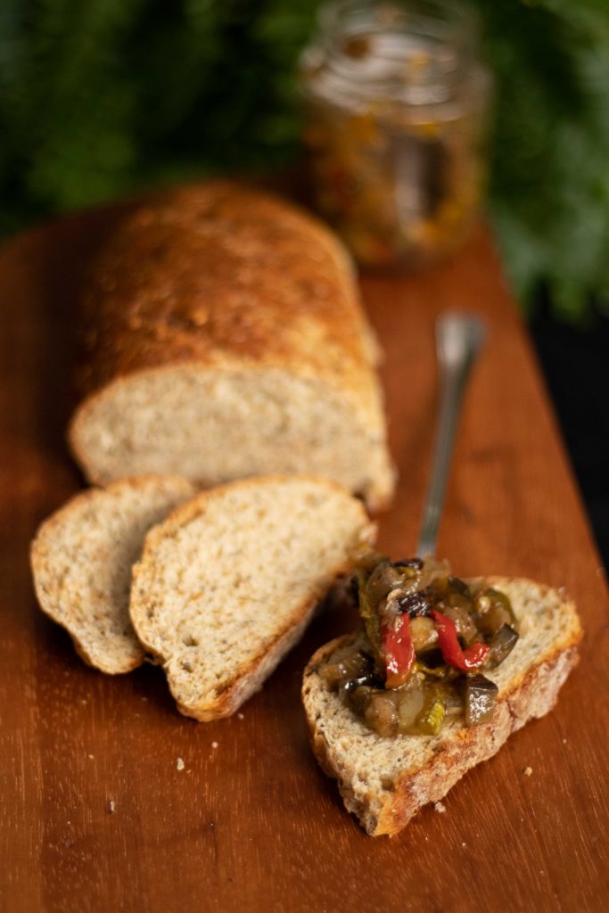 foto de um pão integral multigrãos fatiado e servido juntamente com caponata